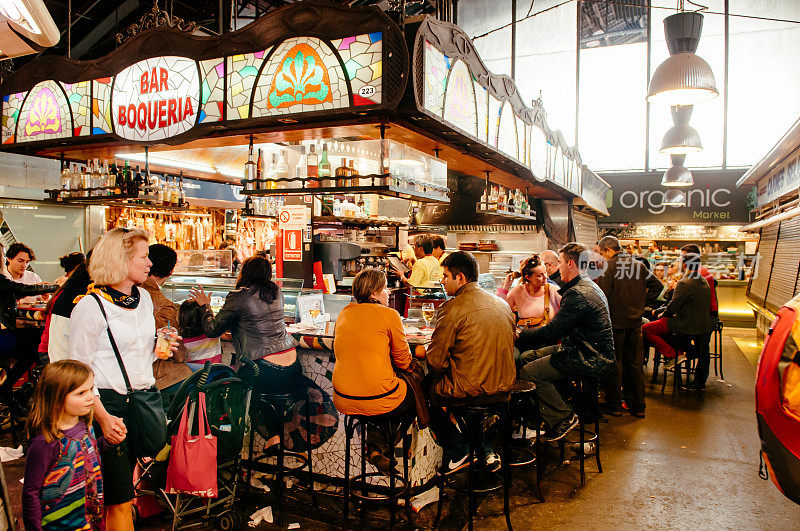 许多游客在Tapas酒吧餐厅在梅尔卡多de La Boqueria市场-巴塞罗那，西班牙